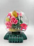 Le Rosarium France Decorative vintage floral arrangement under a clear glass dome with a glossy green base