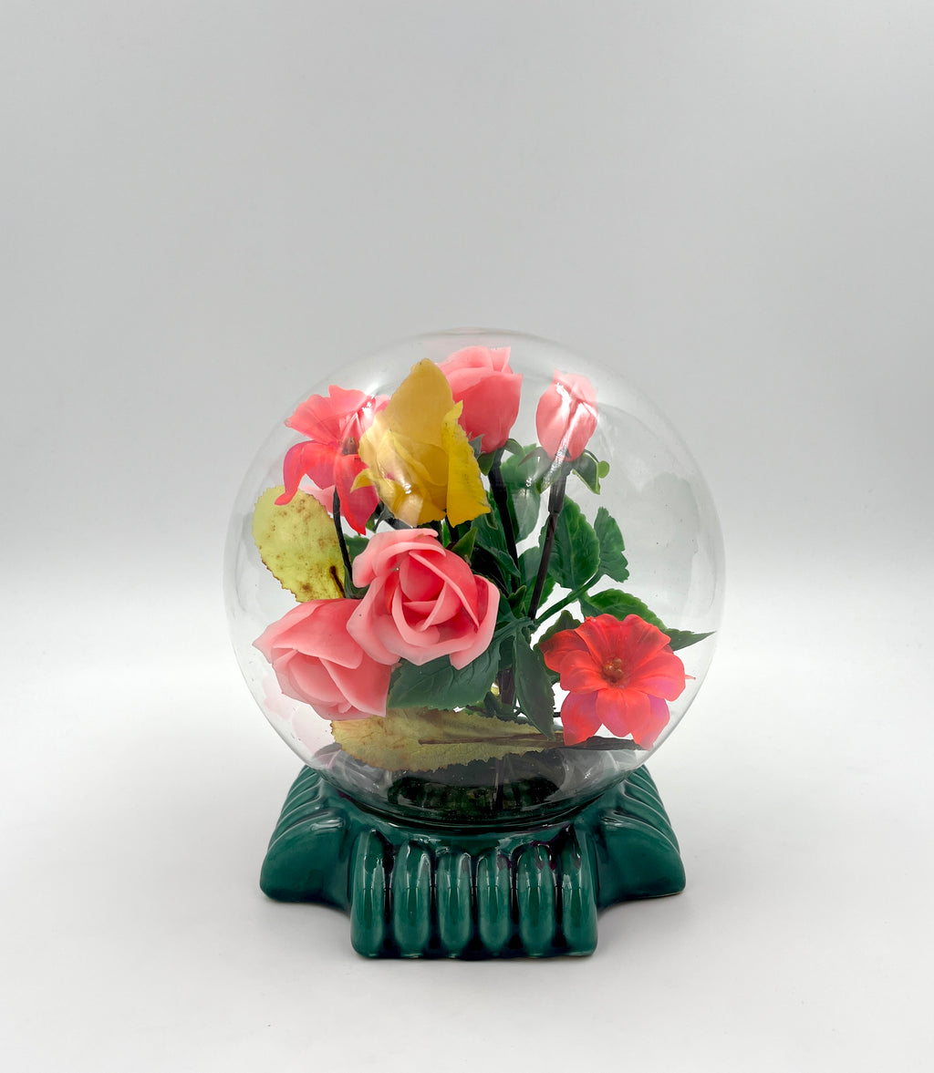 Le Rosarium France Decorative vintage floral arrangement under a clear glass dome with a glossy green base