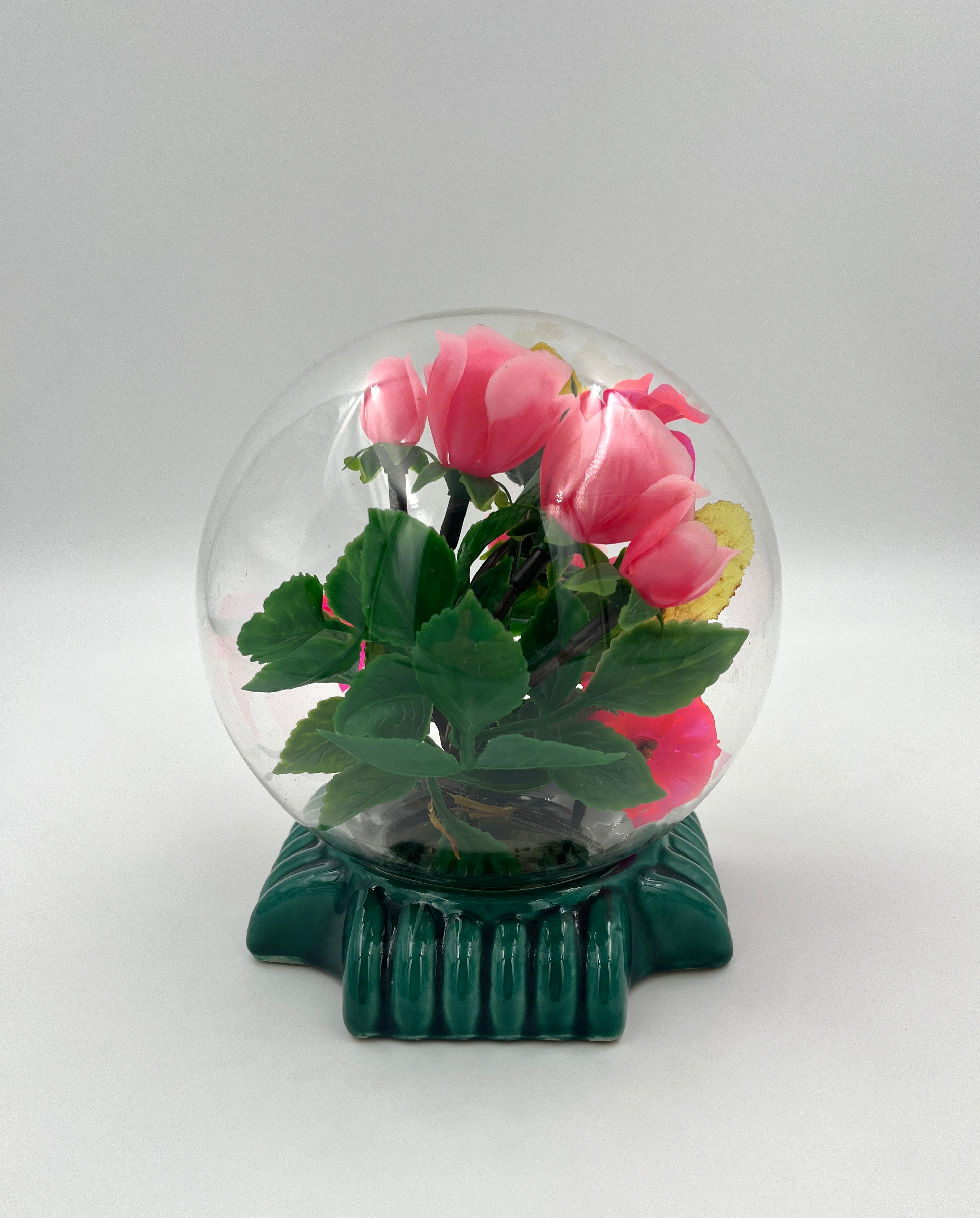 Le Rosarium France Decorative vintage floral arrangement under a clear glass dome with a glossy green base