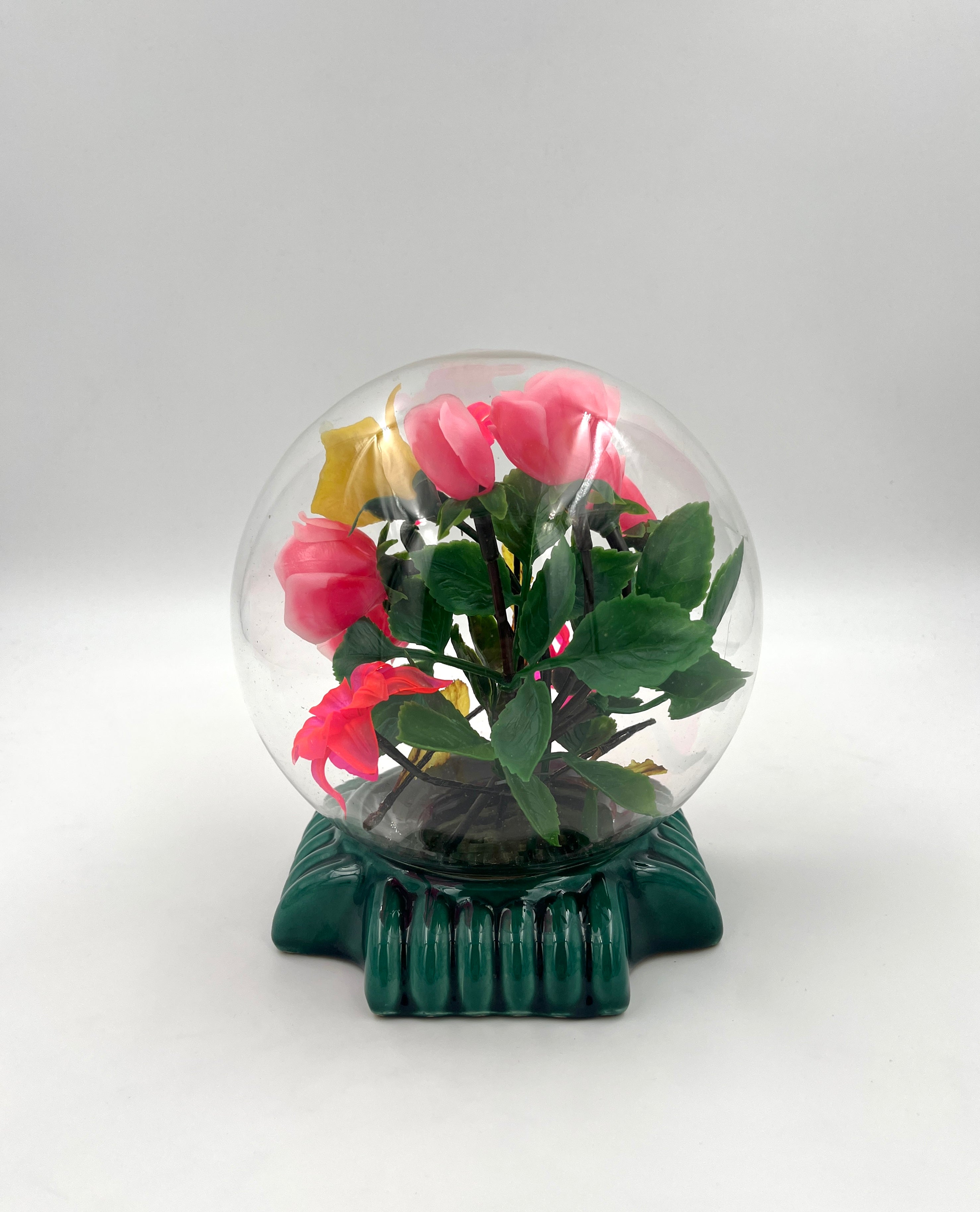 Le Rosarium France Decorative vintage floral arrangement under a clear glass dome with a glossy green base